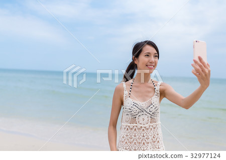 Woman taking selfie by mobile phone with the sea 32977124
