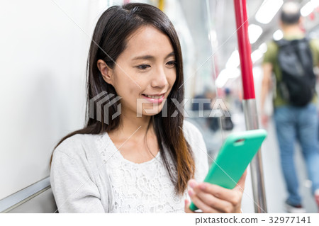 Woman uisng mobile phone on train 32977141