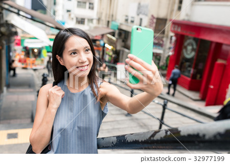 Woman taking photo with cellphone in Pottinger Street Woman taking photo with cellphone in Pottinger Street 32977199