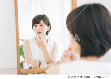 A woman applying lipstick A woman applying lipstick 32981256