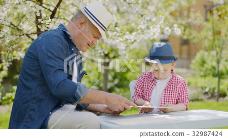 Granddad and his grandson are making wooden plane 32987424