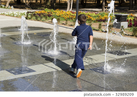 The boy runs around in the fountain The boy runs around in the fountain 32989209