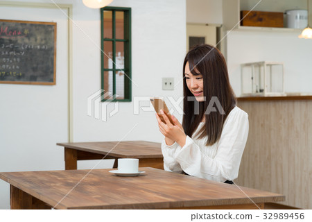 A woman watching a smartphone at a cafe 32989456