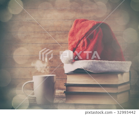Santas hat over books near hot cup of coffee Santas hat over books near hot cup of coffee 32993442