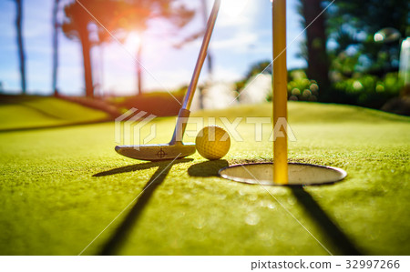 Mini Golf yellow ball with a bat near the hole  32997266