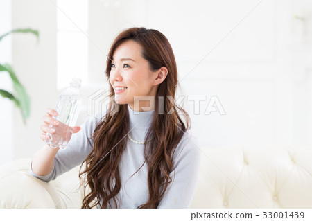 A woman drinking water in a room 33001439