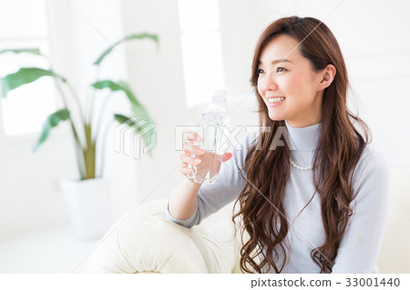 A woman drinking water in a room A woman drinking water in a room 33001440