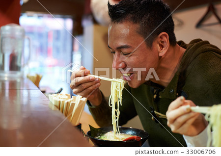 A man is eating ramen and smiling 33006706