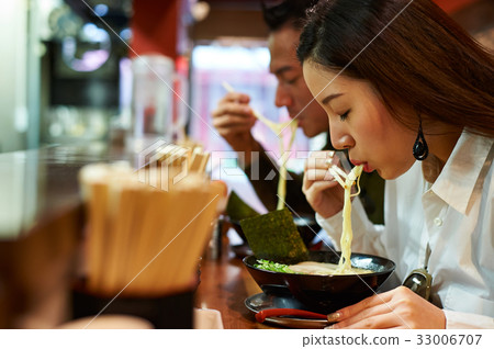 A photo of a couple eating ramen at a restaurant 33006707
