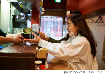 a couple is getting a bowl of food from someone 33006734