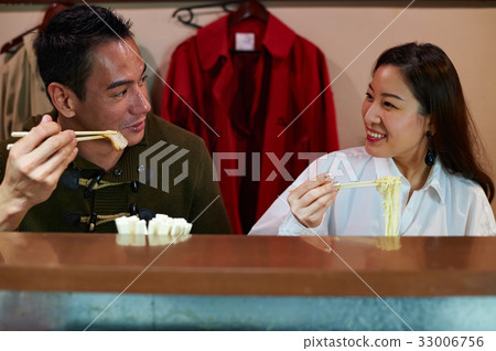 a couple is picking up food, looking at each other and smiling a couple is picking up food, looking at each other and smiling 33006756