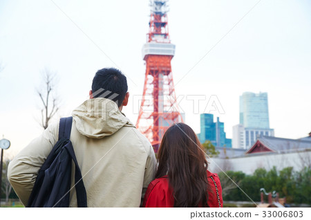 a photo of a couple standing and sightseeing near the tower 33006803
