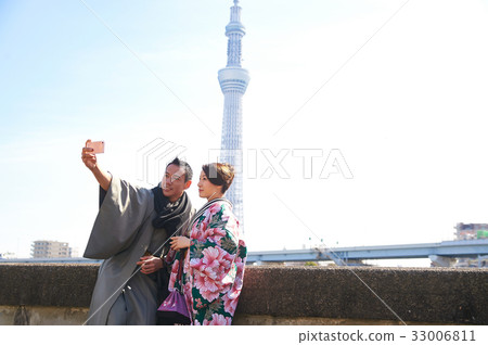 young couple in kimono is taking selfie outdoors 33006811