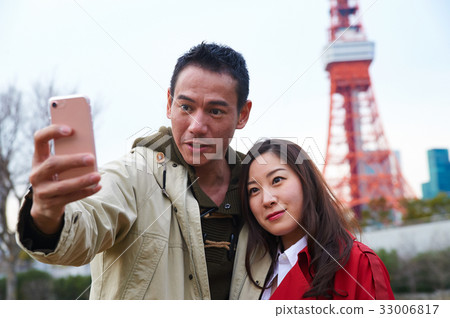 A beautiful couple takes selfie near Tokyo tower 33006817