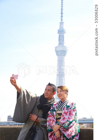 A couple in kimono is taking selfie near white tower A couple in kimono is taking selfie near white tower 33006829