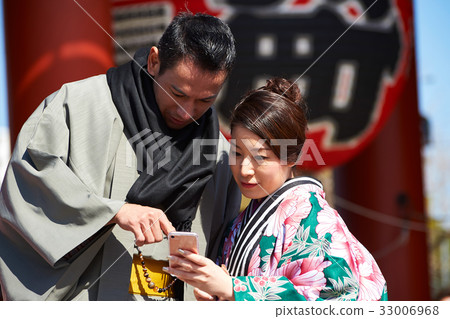 The portrait of man and woman in kimono looking at smartphone The portrait of man and woman in kimono looking at smartphone 33006968