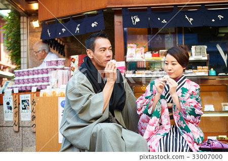 A photo of a couple in kimono eating and thinking about something. A photo of a couple in kimono eating and thinking about something. 33007000