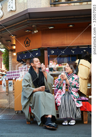 A couple in kimono is sitting and chatting while eating happily. A couple in kimono is sitting and chatting while eating happily. 33007003