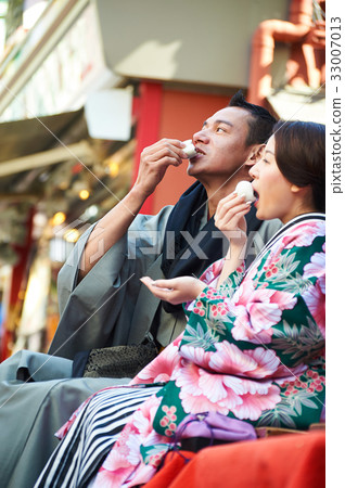 A photo of a couple in kimono eating the same food while relaxing. A photo of a couple in kimono eating the same food while relaxing. 33007013