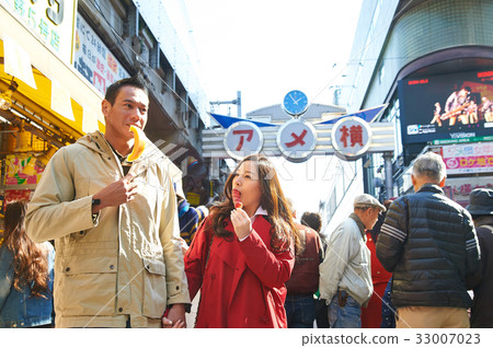 a photo of a couple eating on a street. a photo of a couple eating on a street. 33007023