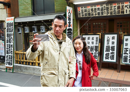 a picture of a couple taking photo outdoors. 33007063