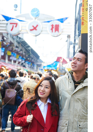 a portrait of a couple staring at something on a street 33007067