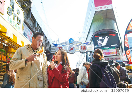 a couple is eating food on the crowded street 33007079