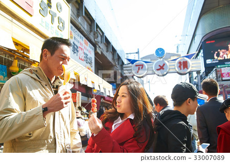 a photo of a couple eating outside the street 33007089
