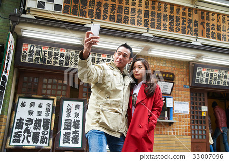 a photo of a couple standing outdoors and taking selfie 33007096