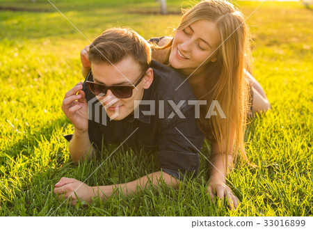 attractive couple of teenagers lying in the grass 33016899