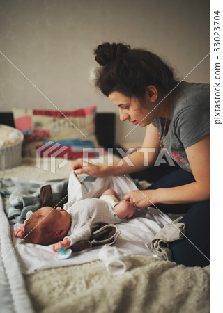 young mother change baby clothes 33023704