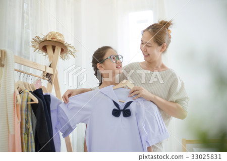 Asian mother helping daughter dressing uniform Asian mother helping daughter dressing uniform 33025831
