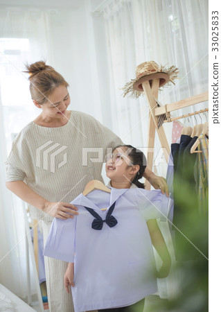 Asian mother helping daughter dressing uniform Asian mother helping daughter dressing uniform 33025833