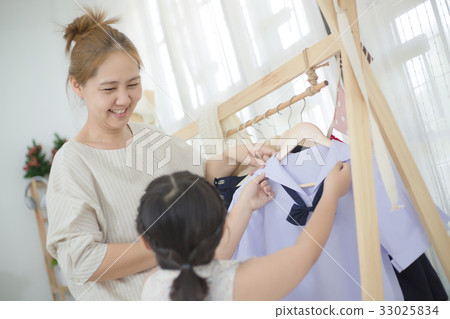 Asian mother helping daughter dressing uniform Asian mother helping daughter dressing uniform 33025834