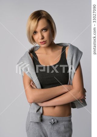 Model woman in sportswear posing indoors on gray Model woman in sportswear posing indoors on gray 33027090