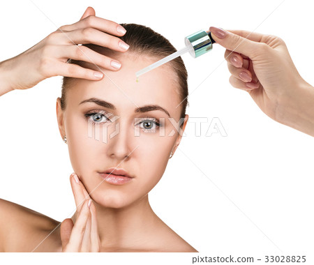 Cosmetic oil applying on face of young woman. Cosmetic oil applying on face of young woman. 33028825