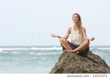 Girl sit at the seaside on the rock and meditating Girl sit at the seaside on the rock and meditating 33033072