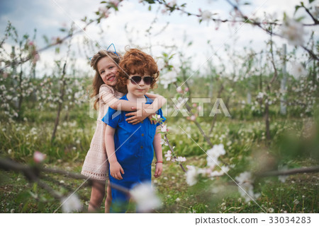little boy and girl in blooming garden little boy and girl in blooming garden 33034283