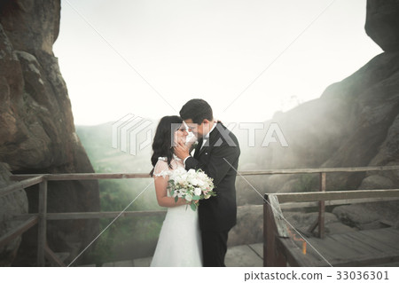Happy wedding couple kissing and hugging near a Happy wedding couple kissing and hugging near a 33036301