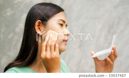 Asian women to apply pressed powder. 33037487
