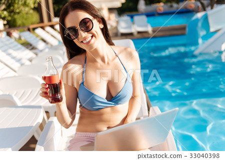 Cheerful young woman raising a bottle of soda 33040398