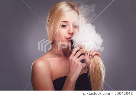 Young sexy blonde is vaping. Studio shooting, - Stock Photo [33042048]