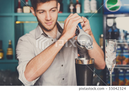 Bartender making cocktail with lime, close-up 33042324