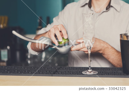 Bartender making cocktail with lime, close-up 33042325