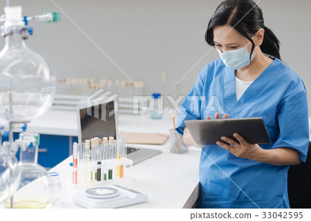 Serious smart biologist working on a tablet 33042595