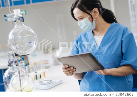 Pleasant hard working scientist looking at flasks 33042602