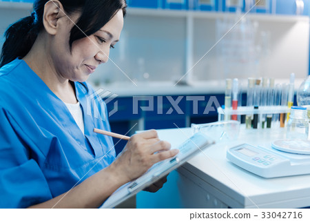 Joyful nice woman writing in her notebook 33042716