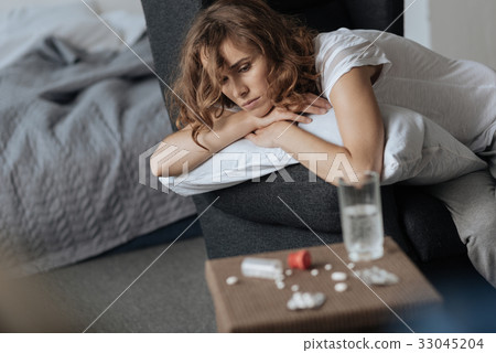 Upset moody woman looking at her bedside table 33045204