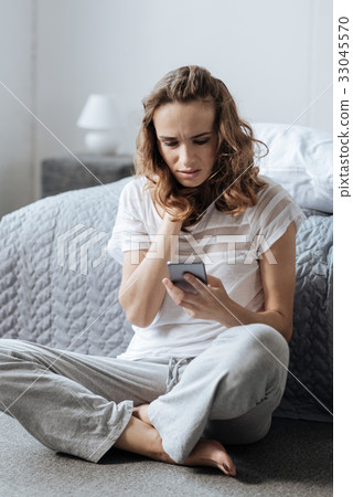 Cheerless attractive woman sitting on the floor 33045570
