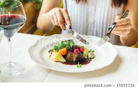 women eating beef steak with berry sauce women eating beef steak with berry sauce 33055716